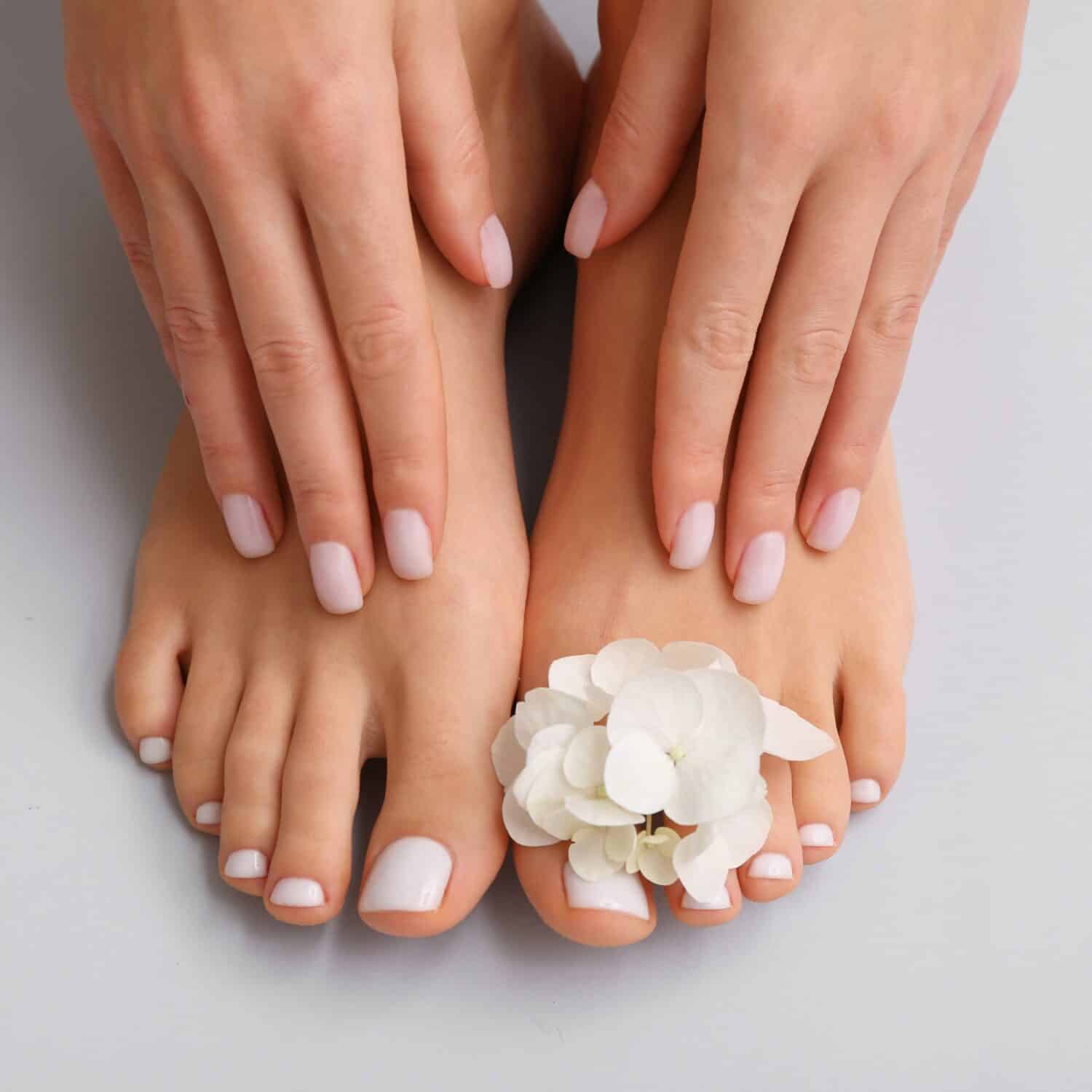 Beautiful nails and toes adorned with a delicate white flower accent.