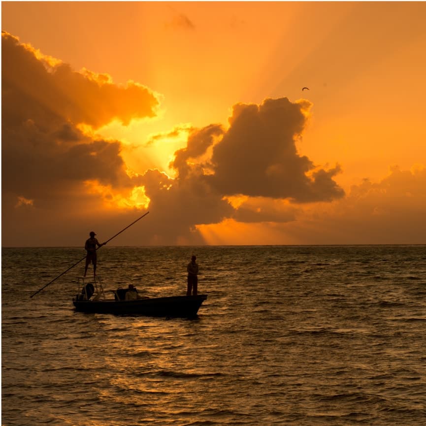 Fishermen enjoying a peaceful sunset on calm waters.