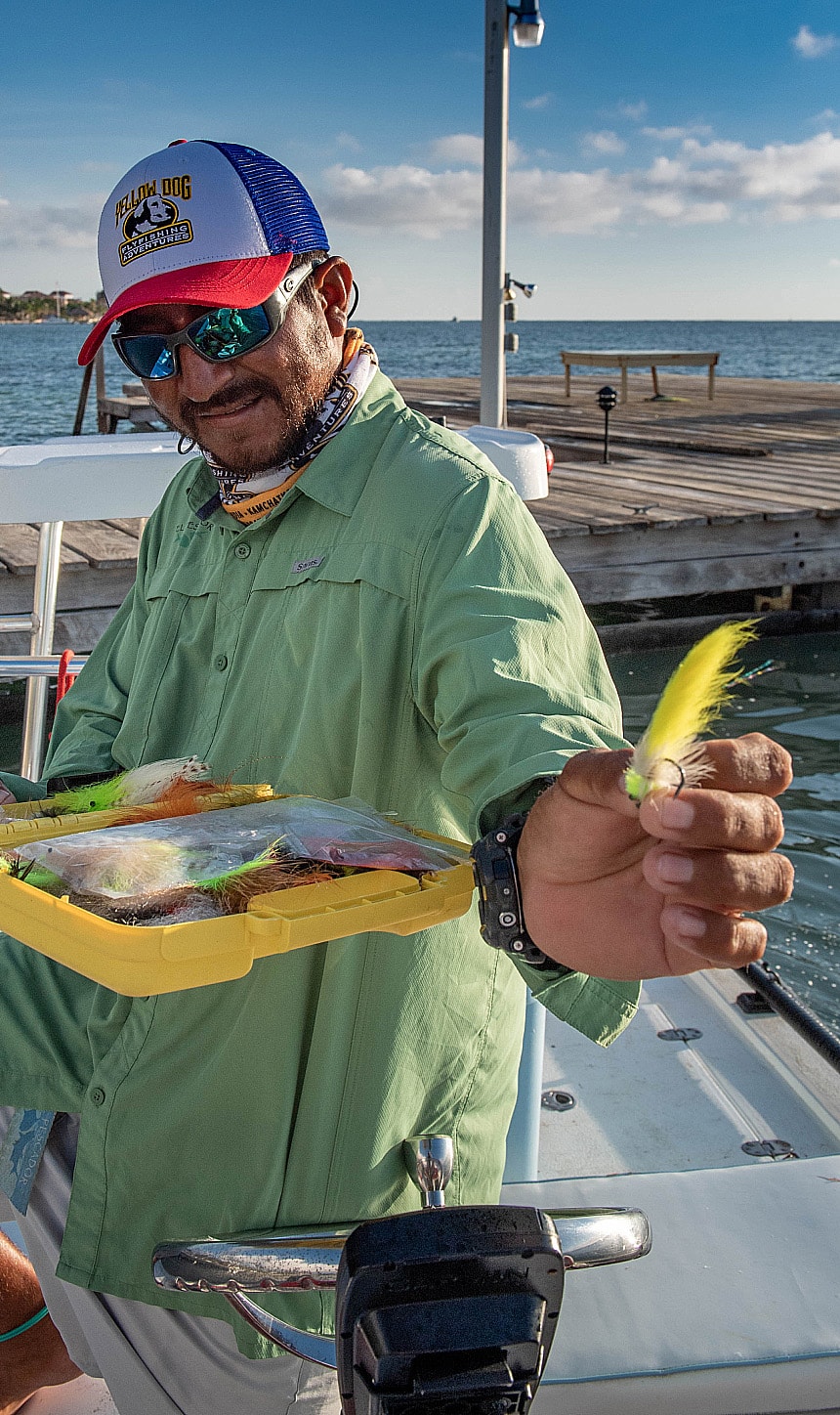 Expert angler showcasing colorful fishing lures on a boat by the water.