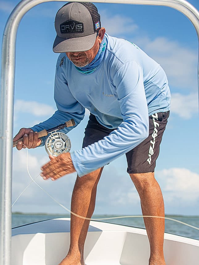 Angler prepares for fly fishing on a sunny day, showcasing skill and technique.