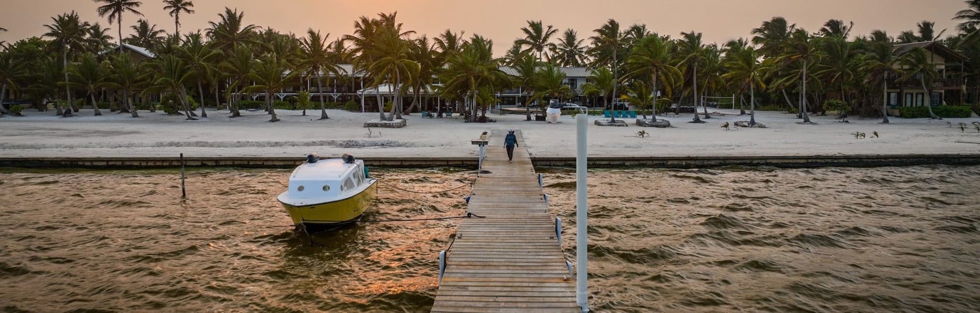 Relaxing sunset view at El Pescador Beach, with boats and palm trees lining the shore.