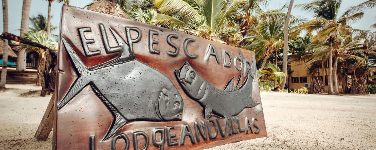 El Pescador Lodge beach sign featuring carved fish art.