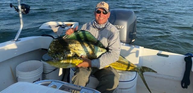 Successful fishing trip with a proud angler and a large Mahi Mahi catch.