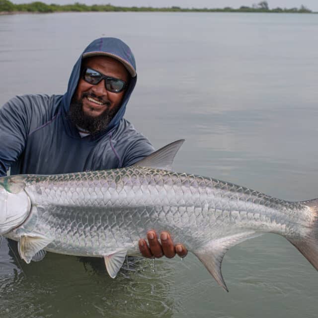 http://Angler%20proudly%20holds%20a%20large%20tarpon%20in%20serene%20waters.