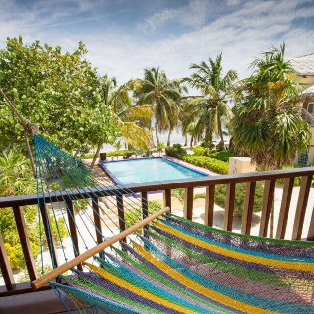http://Colorful%20hammock%20overlooking%20a%20serene%20pool%20surrounded%20by%20lush%20tropical%20greenery.