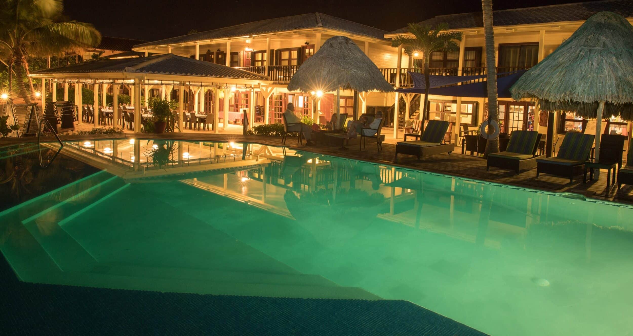 Serene tropical resort pool illuminated at night under a stunning starry sky.