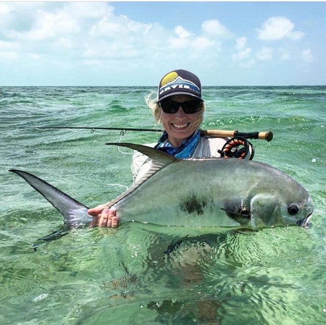 Angler celebrates a successful catch in crystal-clear water with a stunning fish.