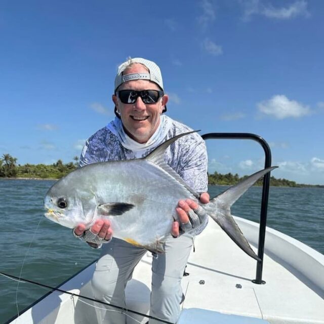 Successful angler proudly displays a beautiful fish on a sunny day.