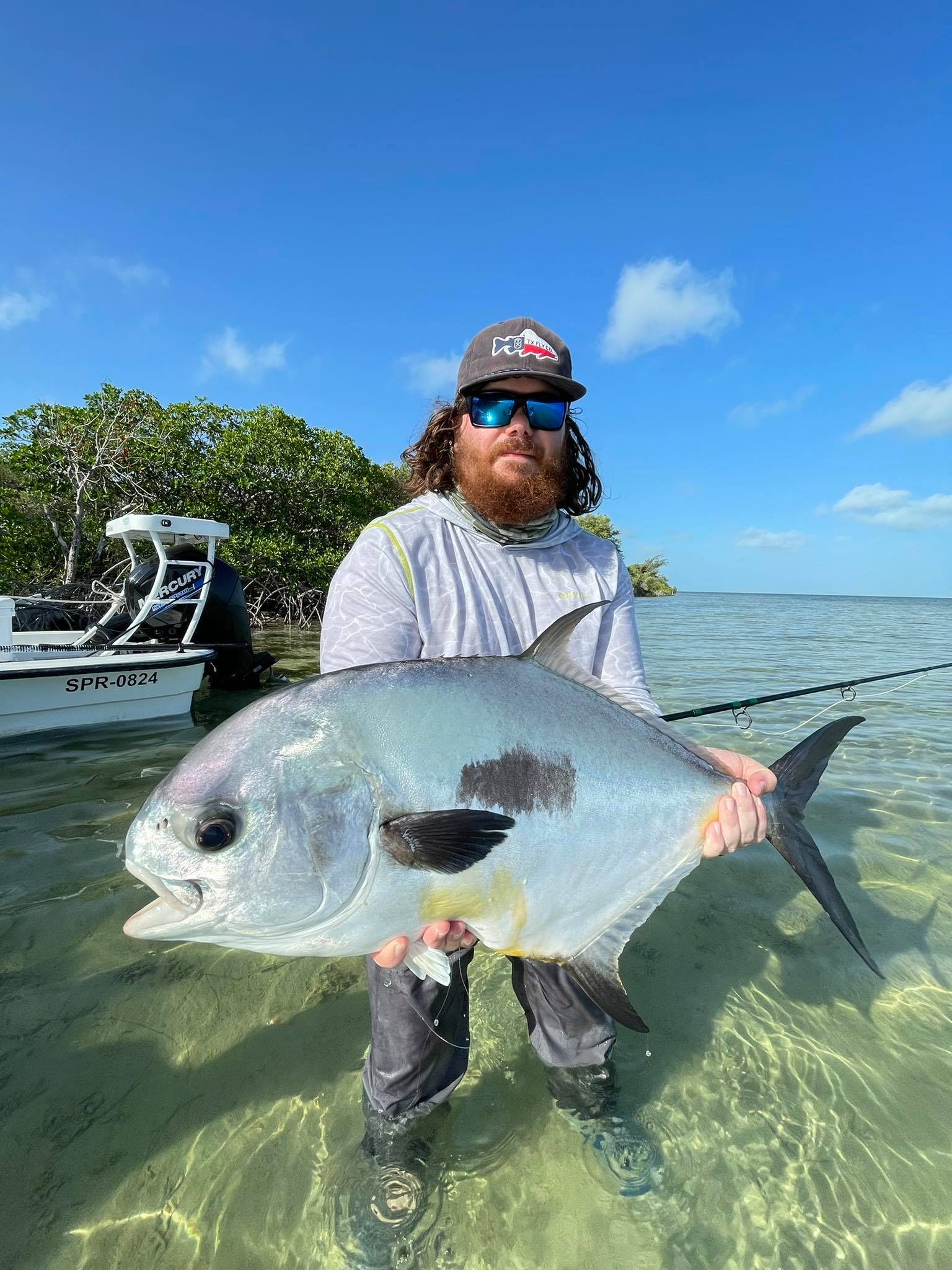 Angler proudly holds a beautiful permit fish in crystal-clear waters.