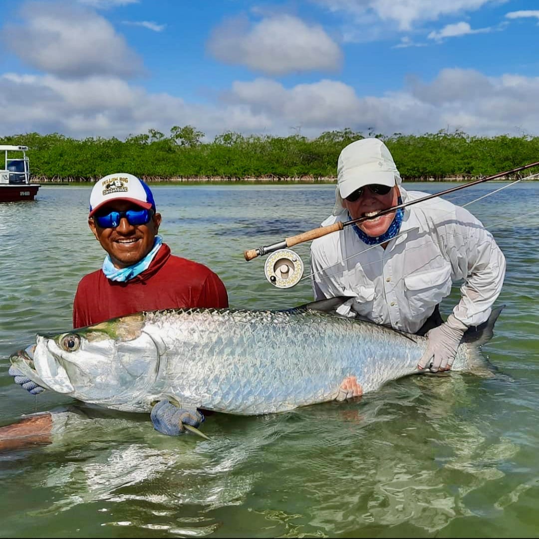 Anglers proudly display their massive tarpon catch during a successful fishing trip.