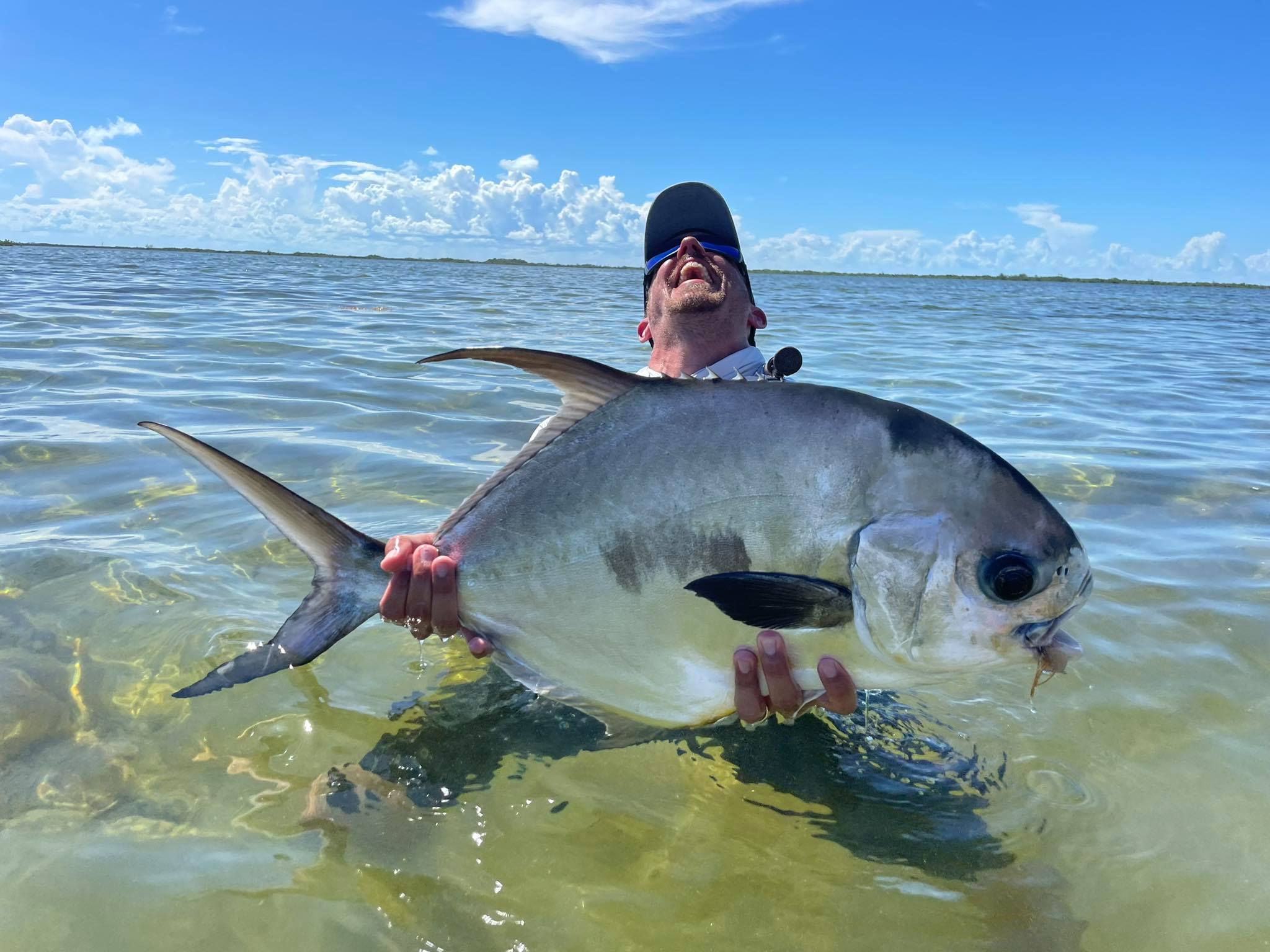 Angler proudly displays a large fish caught in crystal clear waters.