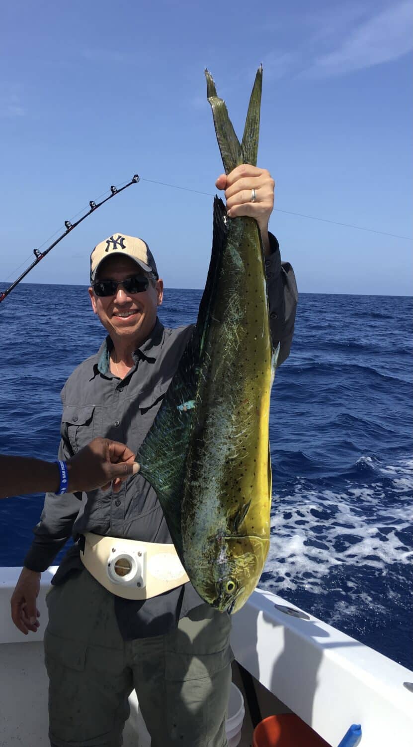 Man proudly holds a large fish caught while deep-sea fishing.