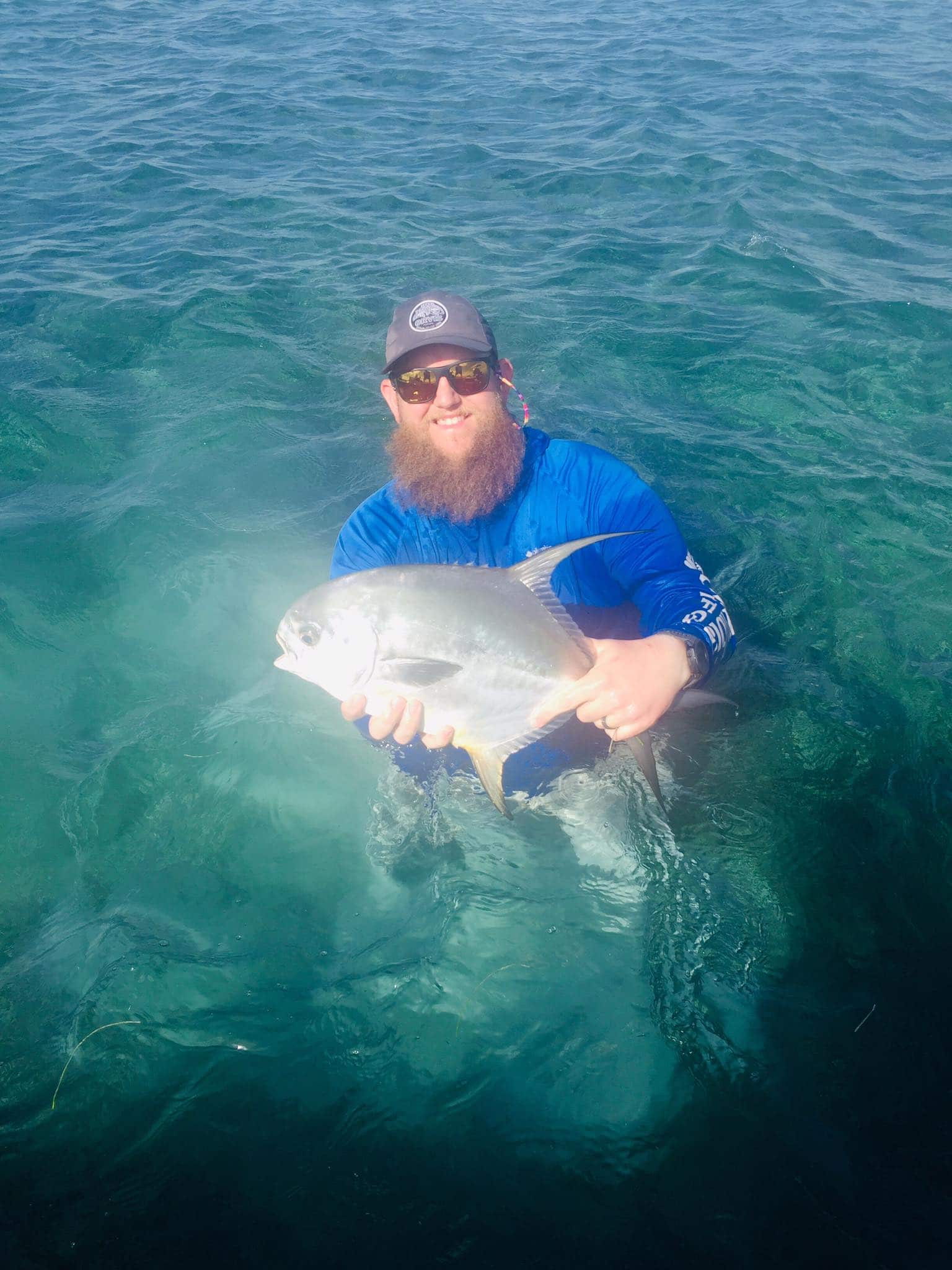 Angler celebrates a successful catch in vibrant, clear waters.