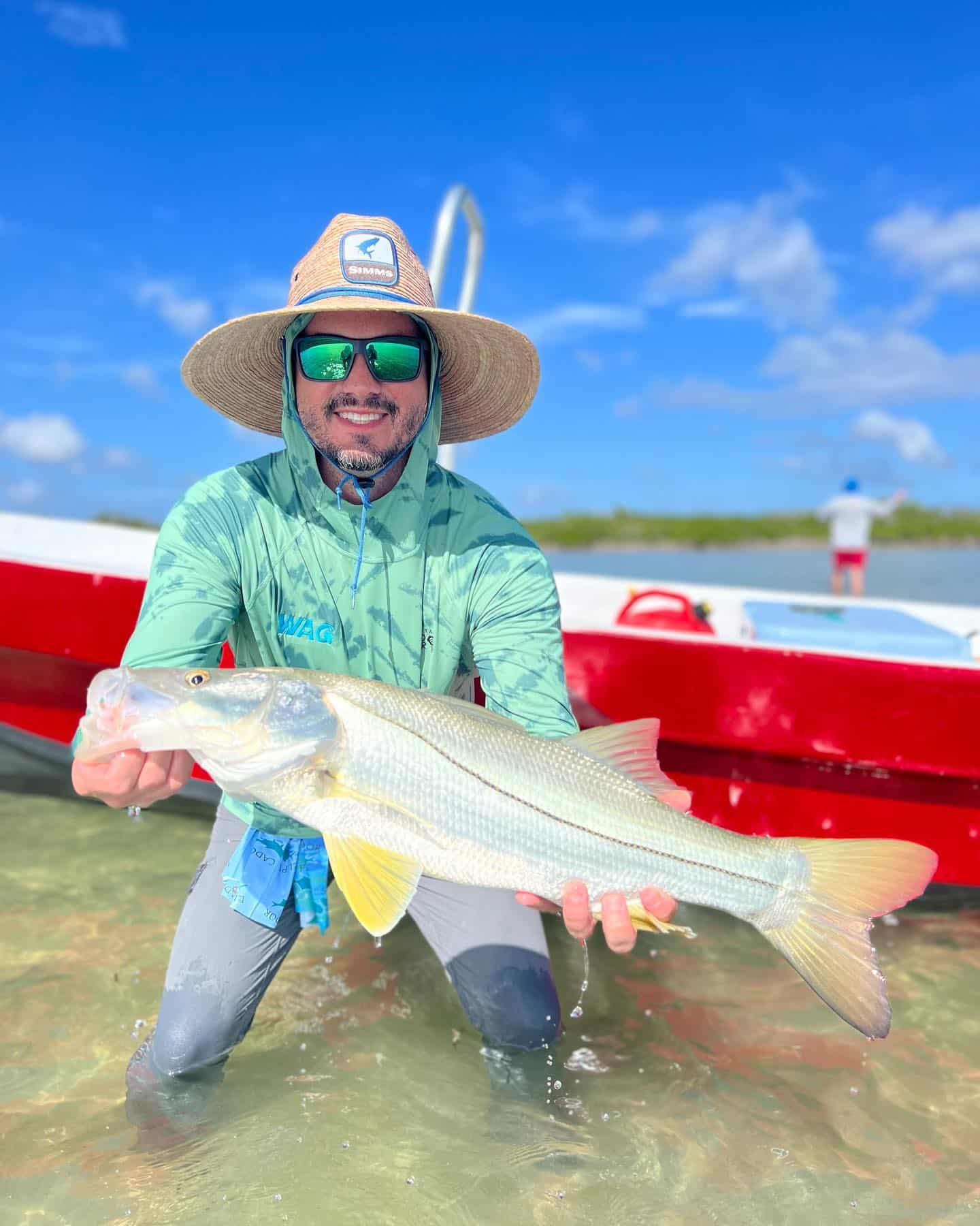 Angler holds a large fish, enjoying a sunny day on the water.