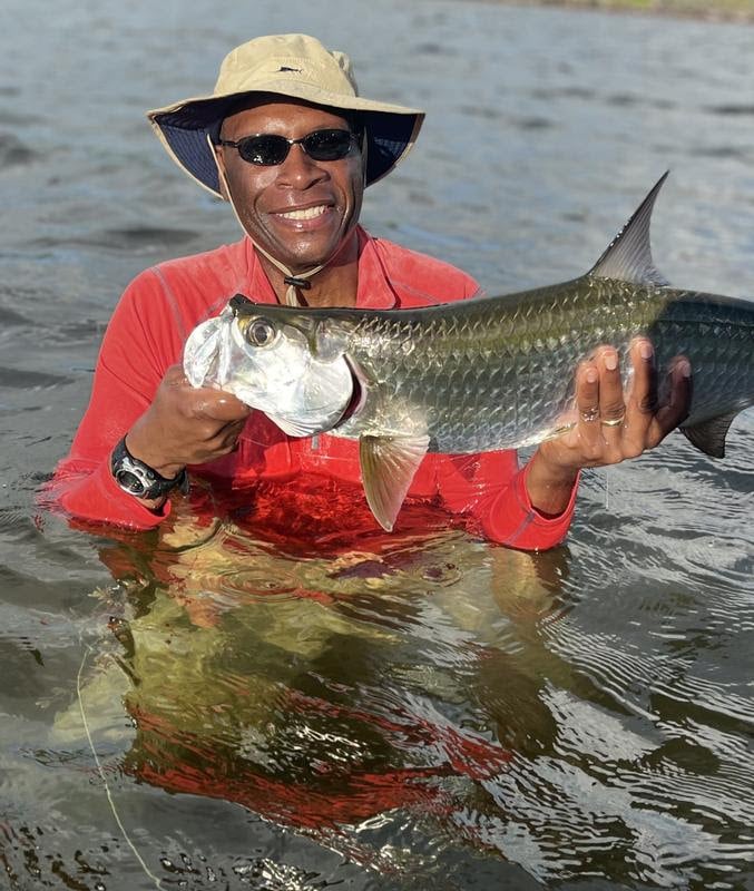 Happy angler proudly holding a large fish in the water.