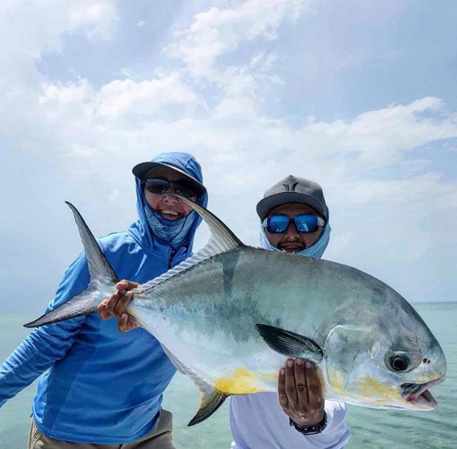 Anglers proudly showcasing their huge catch against a beautiful ocean view.