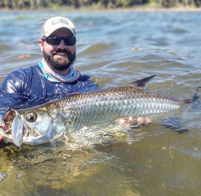 Angler showcasing a massive tarpon caught during an exciting fishing adventure.