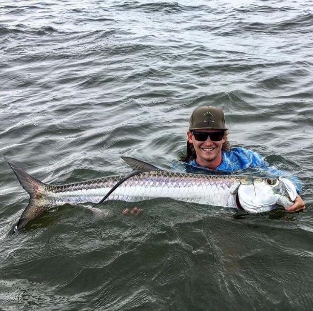 Angler proudly shows off a large tarpon caught while fishing.
