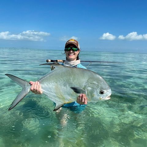 Angler proudly holding a giant fish in crystal-clear waters during an unforgettable fishing trip.