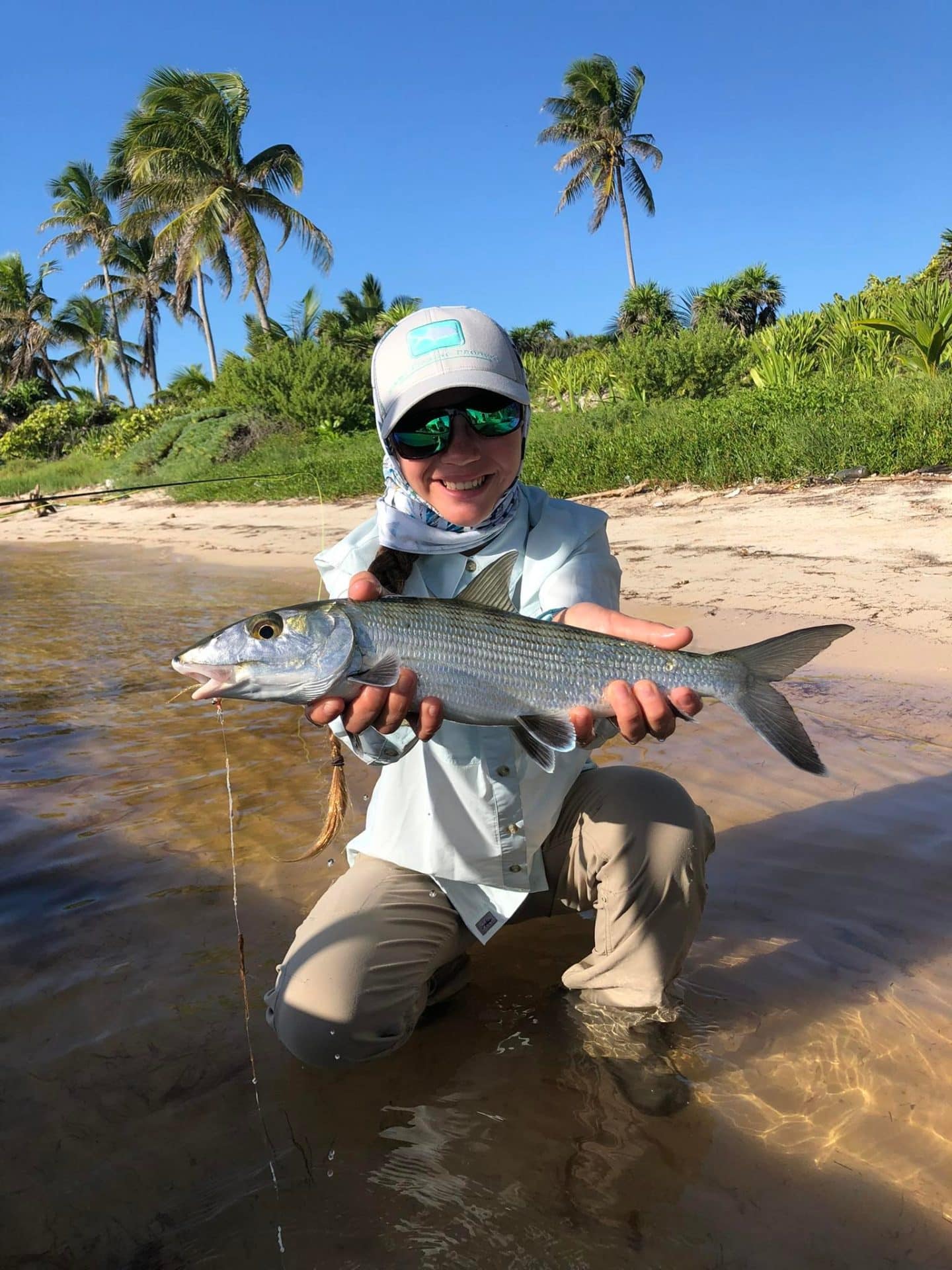 Joyful angler proudly displaying a fresh catch on a sunny beach.