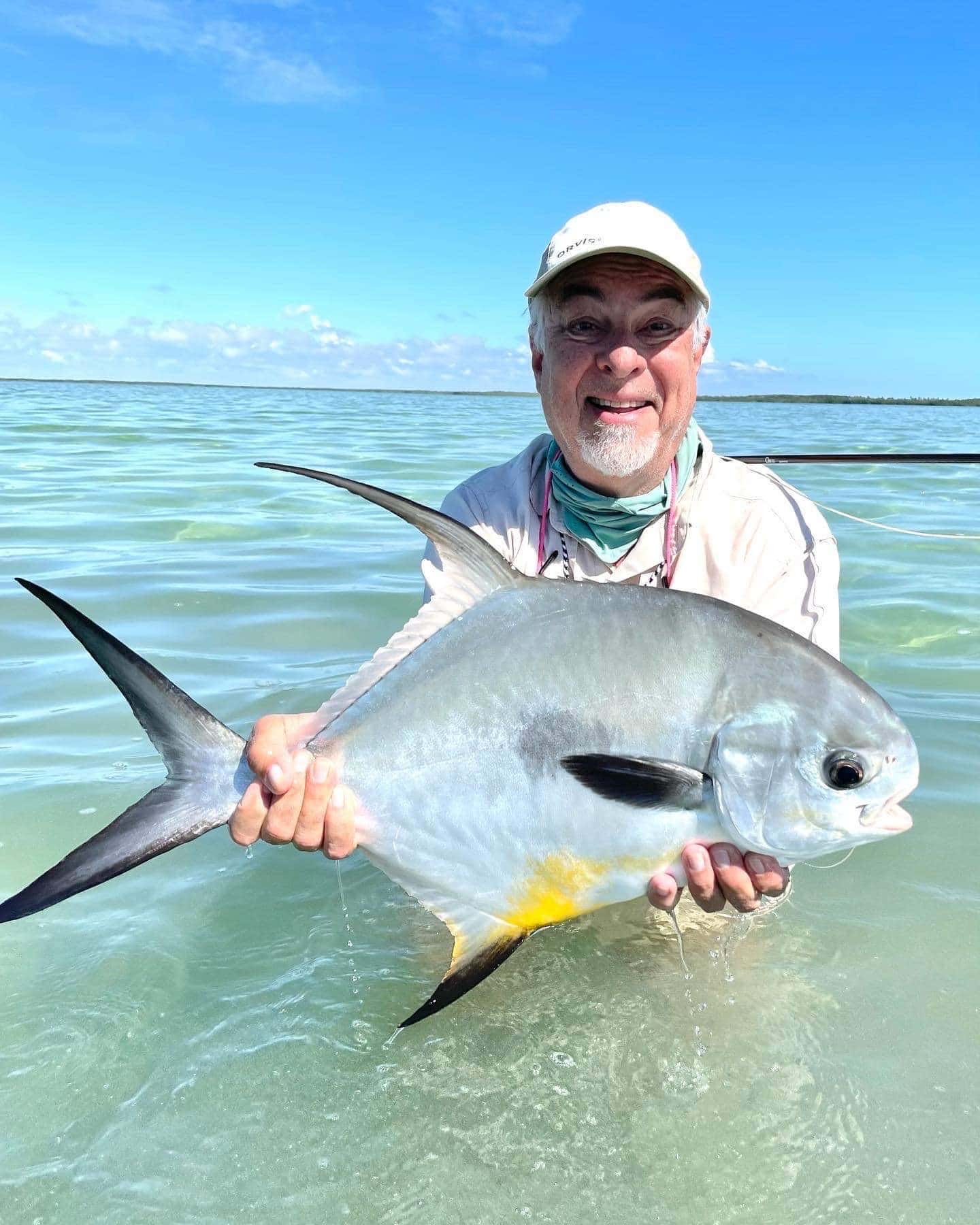 Happy angler proudly holding a vibrant fish in clear waters.