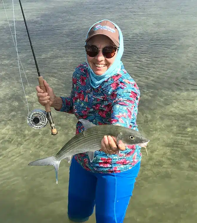 Happy angler proudly holding a fish in clear waters during a fishing trip.