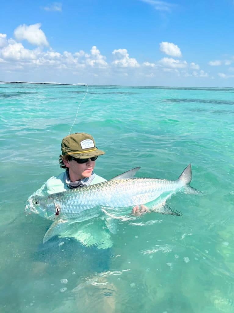 Angler celebrates a stunning fish catch in crystal-clear waters.
