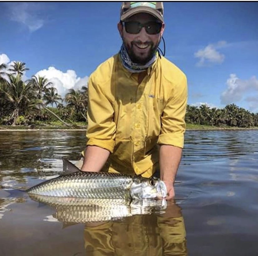 Proud angler holding a beautiful fish in serene waters under a bright sky.