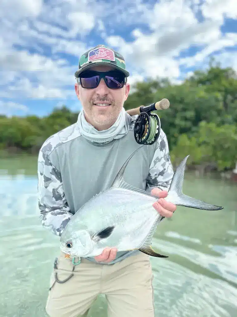 Angler proudly displays a large fish caught in clear, tropical waters.