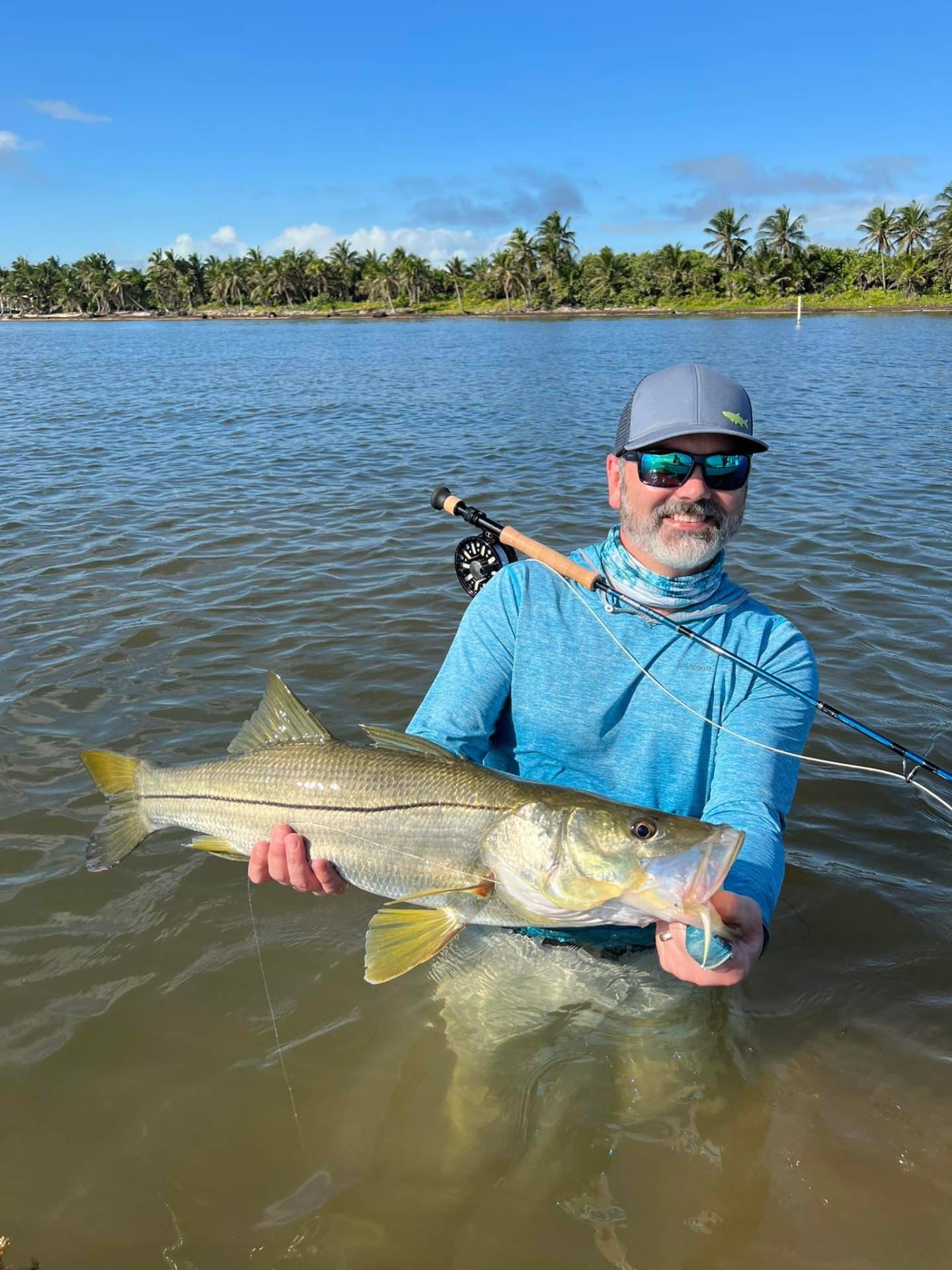 Angler proudly displays a large snook caught in stunning waters.