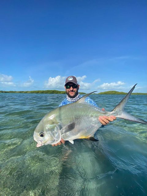 Fisherman showcases a massive fish in stunning crystal-clear waters.