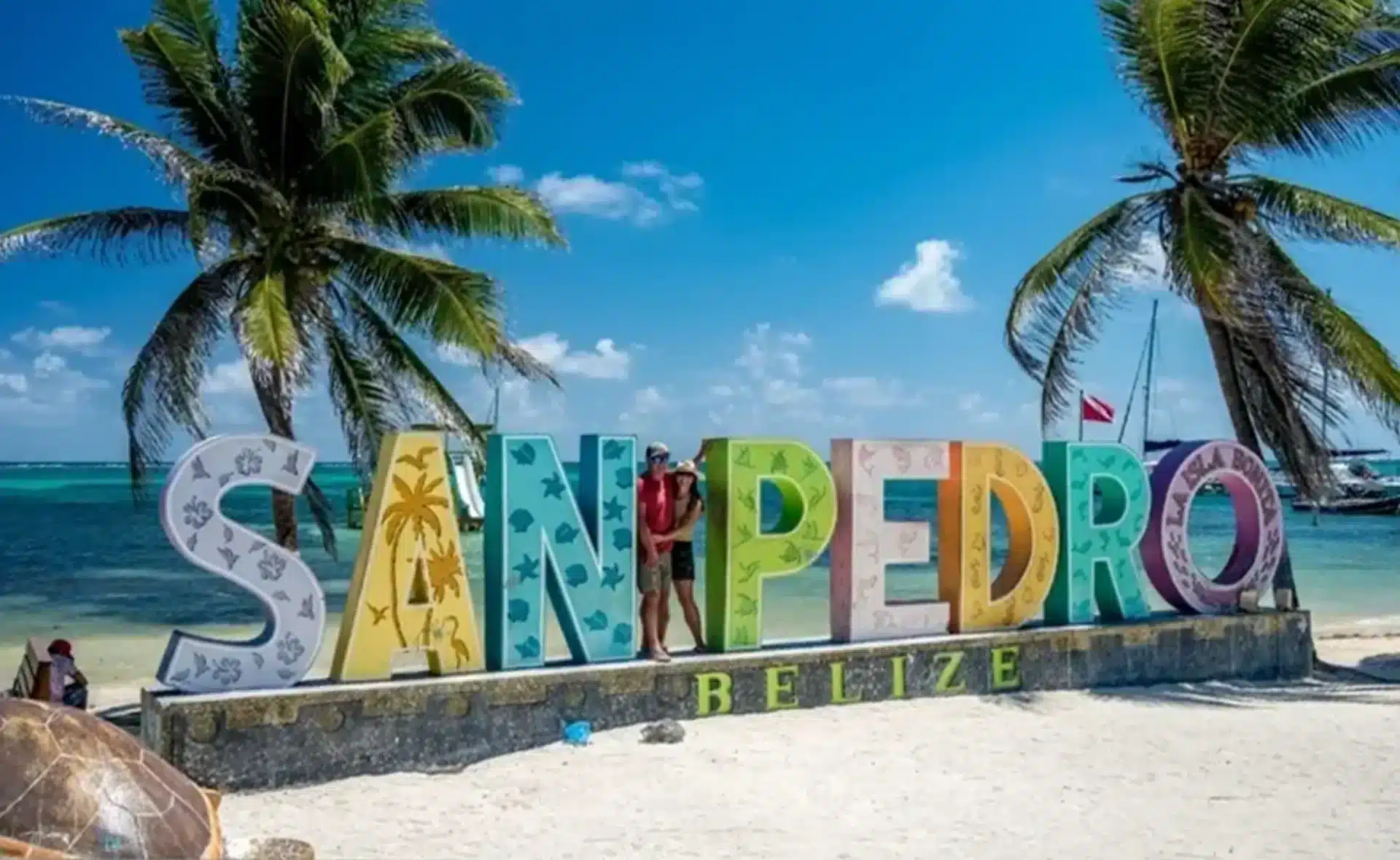 San Pedro Belize beach sign beneath palm trees