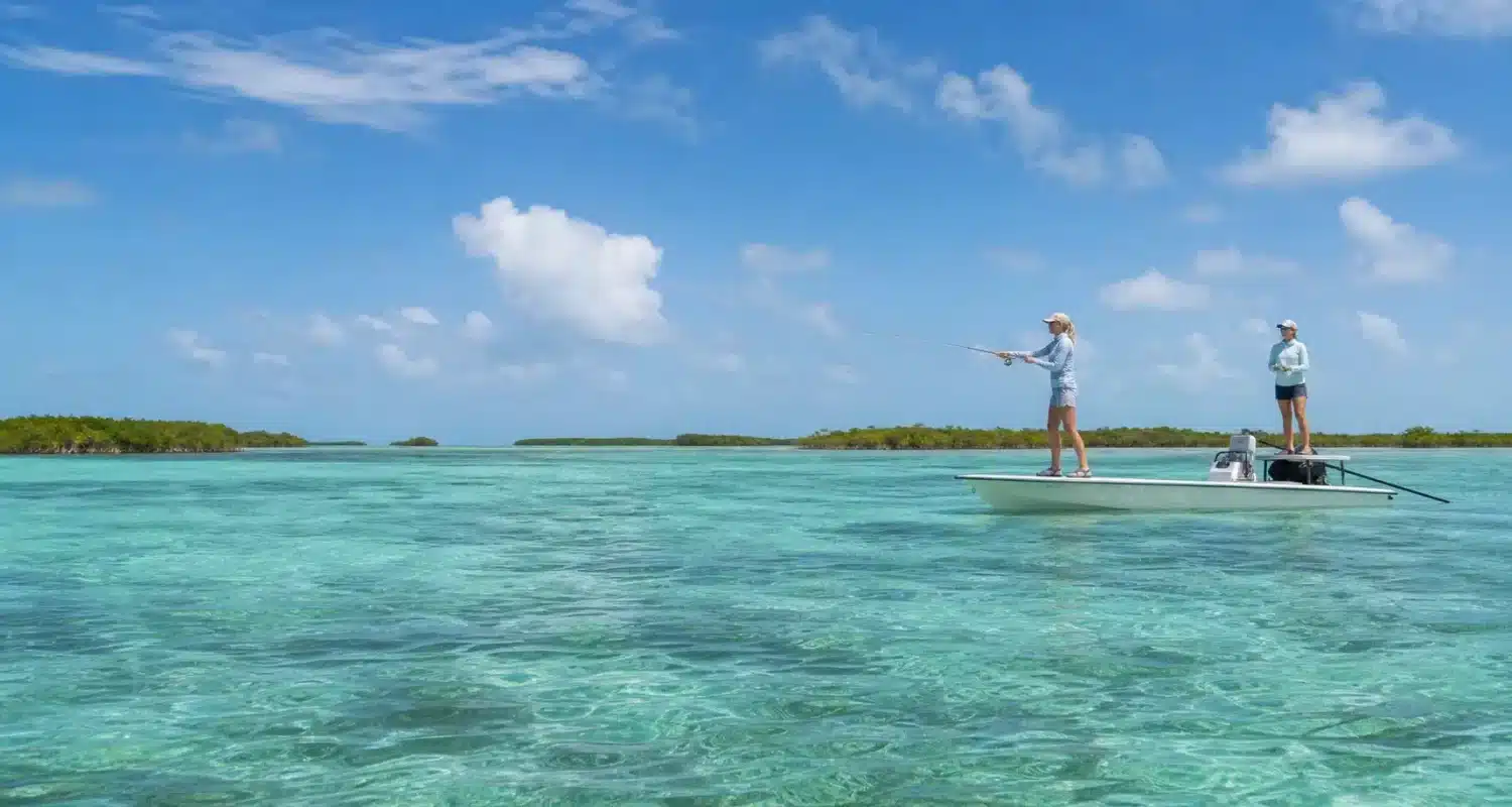 Two women fly fishing from a skiff on Belize's shallow saltwater flats